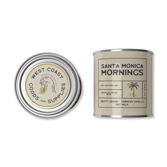 This product is a scented candle from "Kernowfornia Soul Candle Co" with a natural, minimalist design. It features the scent "Santa Monica Mornings" with notes of Sugared Lemon and Oat Milk.  The tin is a pale yellow. Made with 100% natural soy and a crackling wood wick.