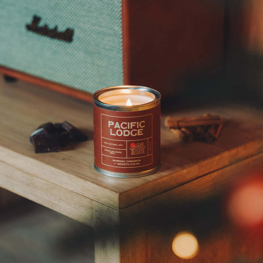 Candle in a Pacific Lodge can on a wooden surface with a blurred background