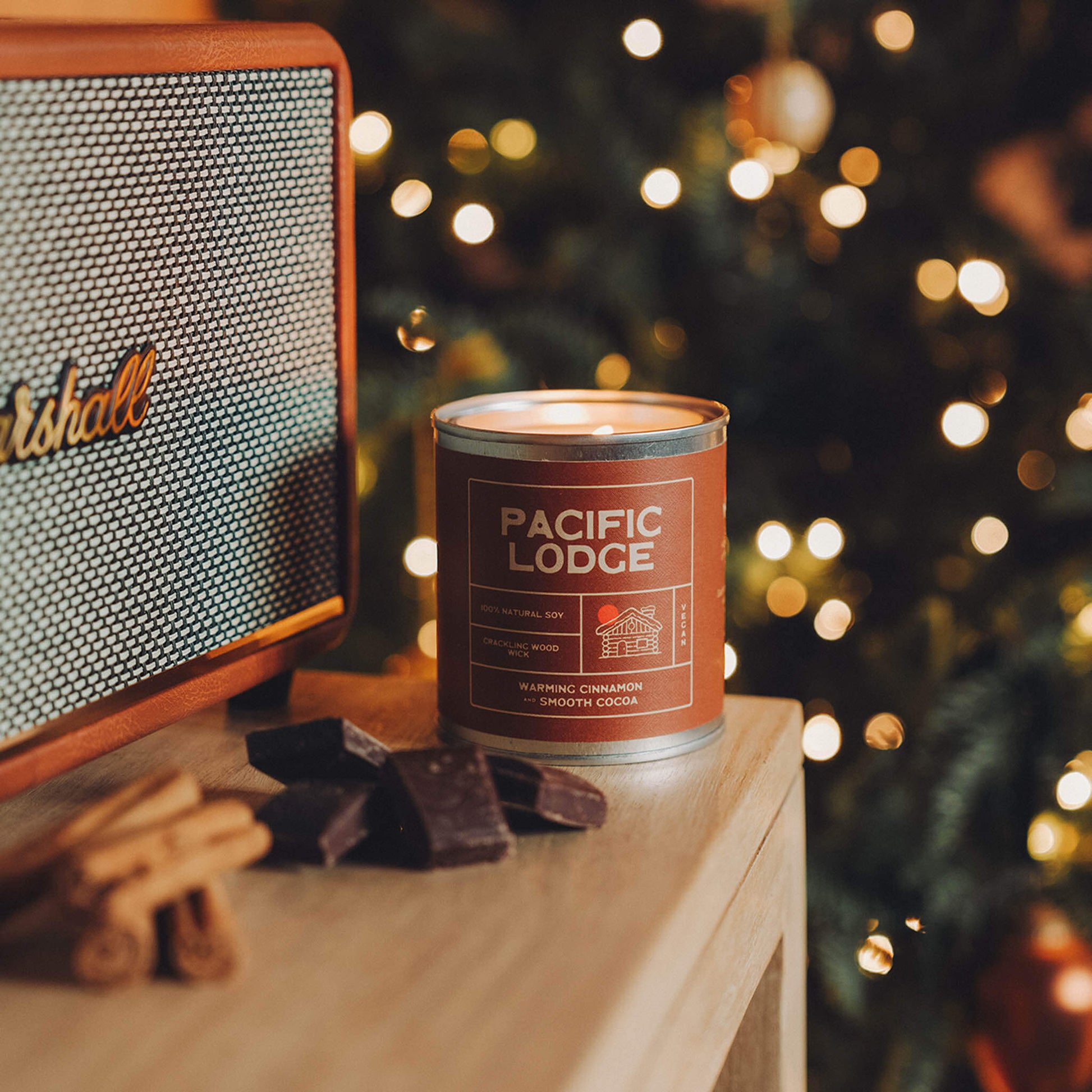 Candle labeled 'Pacific Lodge' next to a Marshall speaker with a blurred Christmas tree in the background